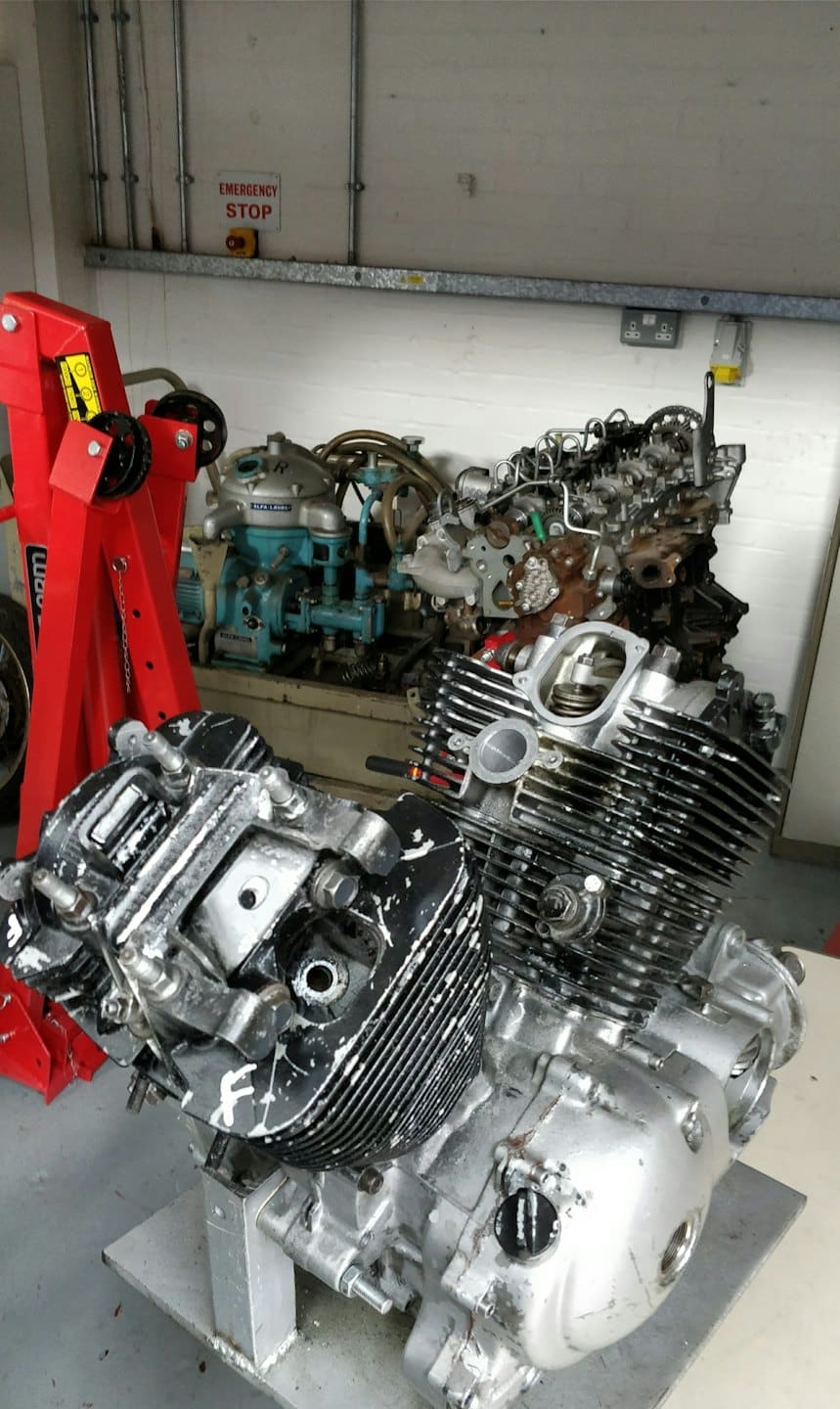 Bir atölyede demonte edilmiş araç motorları ve kırmızı bir vinç.